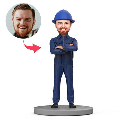 Gebruikersbobblehead van een mechanisch ingenieur in blauwe overalls met gegraveerde tekst, gemaakt door MadeMine.