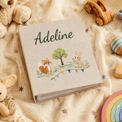Personalized linen baby memory book with embroidered cover, designed as a keepsake album for newborn milestones and memories.
